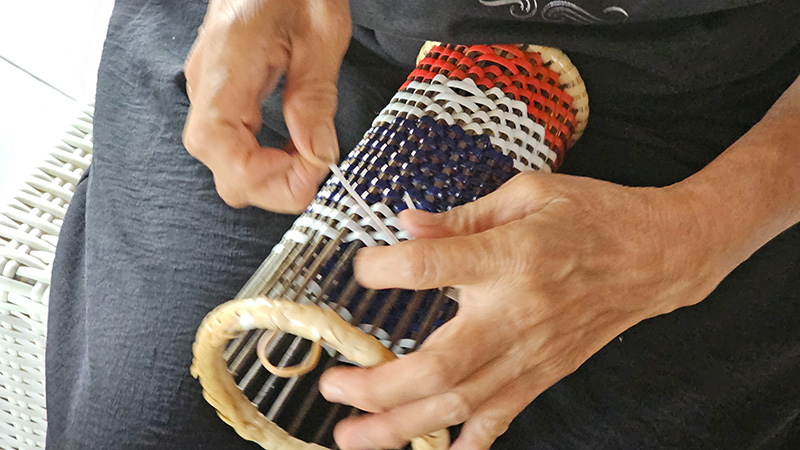Hands working on a traditional woven craft
